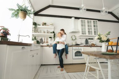 Mutfakta mutlu bir anne-kız olarak çay içip sohbet ediyorlar. Evde yetişkin bir kızı olan yaşlı bir anne.