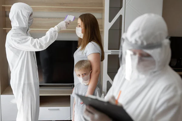 Le médecin vérifie la température corporelle du patient à l'aide d'un thermomètre infrarouge à la maison. Coronavirus, covide-19, quarantaine, température élevée . — Photo