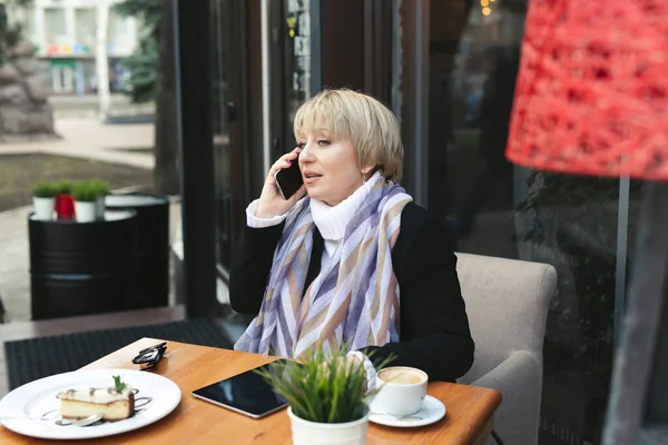 La anciana está hablando por teléfono durante el almuerzo en un café. — Foto de Stock