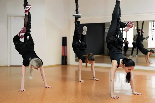 Een close-up groep meisjes hangend aan elastiekjes in de sportschool. Meisjes voeren een moeilijke oefening met bungee gum. — Stockfoto