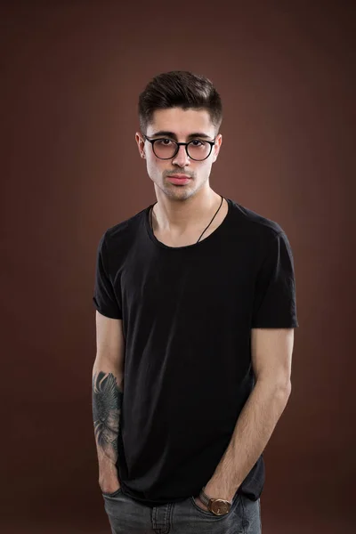 Junger Mann in Depressionen. Stilvoller männlicher Student trägt eine runde Brille, hat eine trendige Frisur, sieht selbstbewusst, isoliert vor braunem Hintergrund aus. Menschen und menschlicher Ausdruck. — Stockfoto