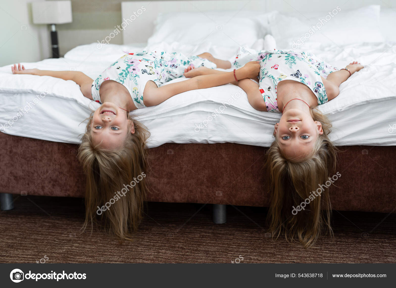 Two twin sisters are lying on the bed upside down — Stock Photo