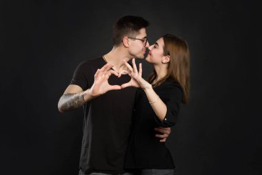 Aşık mutlu çift parmaklarıyla kalp gösteriyor. Elleriyle kalp şekillendiren çiftin yakın çekimi.