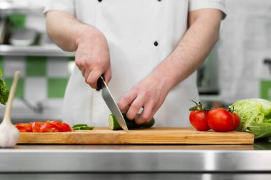 Mutfaktaki şef sebze salatası için taze ve lezzetli sebzeler keser..