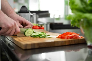 Mutfaktaki şef sebze salatası için taze ve lezzetli sebzeler keser..