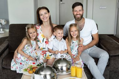 Genç bir aile otel odasında kahvaltı yapar..