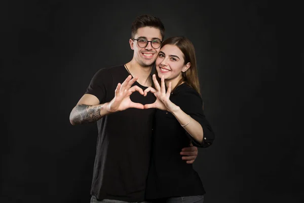 Casal feliz apaixonado mostrando coração com os dedos. Close-up de casal fazendo forma de coração com as mãos — Fotografia de Stock