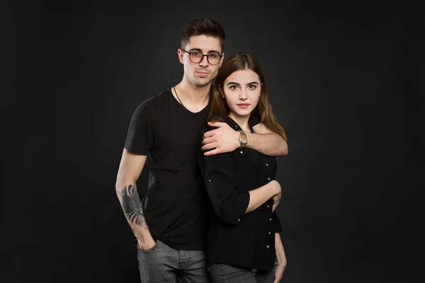 Portret młodej pary w czarnych ubraniach w modne okulary i pozowanie na czarnym tle — Zdjęcie stockowe
