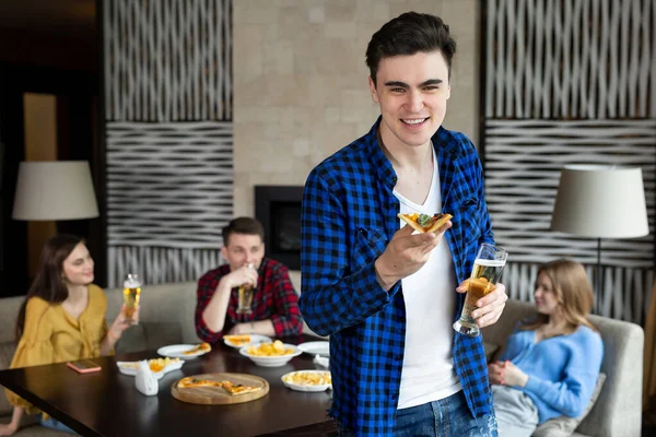 Retrato de um jovem segurando pizza e cerveja em um pub. — Fotografia de Stock