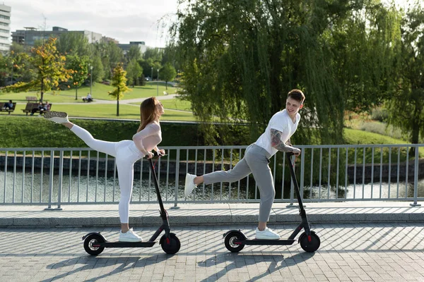 Młoda para na wakacjach zabawia się jeżdżąc skuterem elektrycznym po parku. — Zdjęcie stockowe
