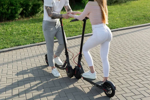 Młoda para w parku na skuterach elektrycznych. — Zdjęcie stockowe