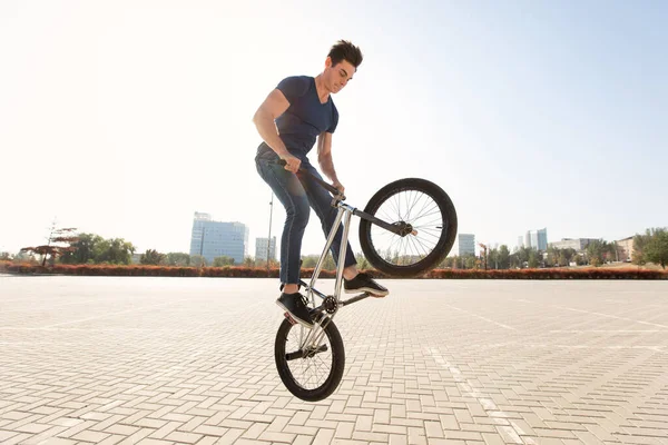 Street portrait of a bmx rider in a jump on the street in the background of the city landscape.