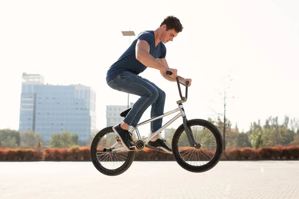 Street portrait of a bmx rider in a jump on the street in the background of the city landscape.