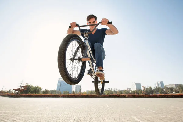 Street portrait of a bmx rider in a jump on the street in the background of the city landscape.