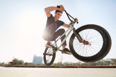 Şehir manzarasının arka planında caddeye atlayan bir BMX sürücüsünün sokak portresi.