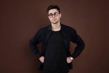 Depresyondaki genç adam. Şık erkek öğrenci yuvarlak gözlük takıyor, modaya uygun saç stiline sahip, kendine güvenen, kahverengi arka planda soyutlanmış görünüyor. İnsanlar ve insan ifadeleri.