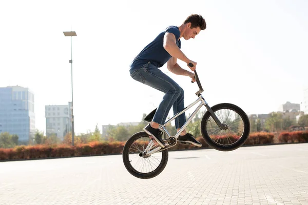 Street portrait of a bmx rider in a jump on the street in the background of the city landscape.