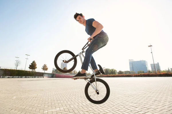 Street portrait of a bmx rider in a jump on the street in the background of the city landscape.