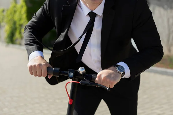 Uomo in giacca e cravatta e occhiali da sole cavalca uno scooter elettrico e ride — Foto Stock
