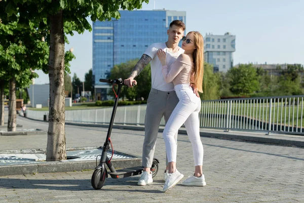 Menina e cara andar em scooters elétricos ao redor da cidade, um casal apaixonado em scooters — Fotografia de Stock