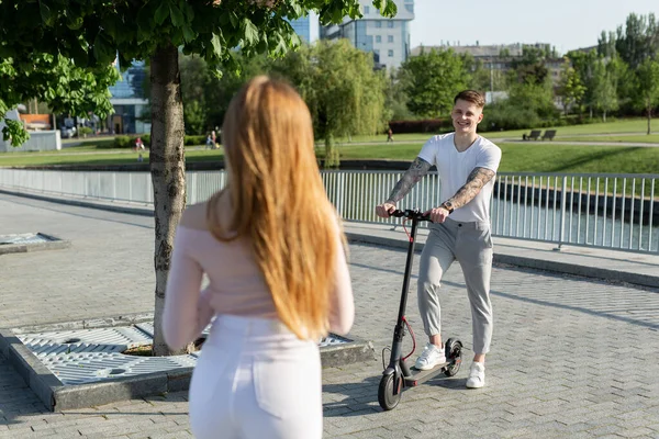 Młoda para w parku na skuterach elektrycznych. — Zdjęcie stockowe