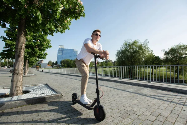 El hombre monta un scooter eléctrico alrededor de la ciudad. — Foto de Stock