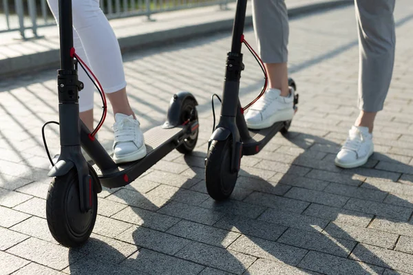 Para mężczyzn i kobiet spaceruje po parku i popycha skutery elektryczne — Zdjęcie stockowe