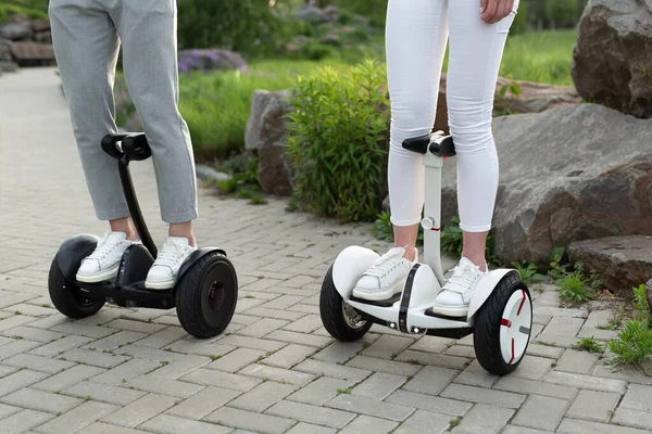 Pernas de homem e mulher montando no Hoverboard para relaxar o tempo juntos ao ar livre na cidade. — Fotografia de Stock