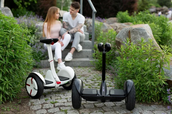 Jongeman en vrouw zoenen in het park. Op de voorgrond hoverboard. — Stockfoto