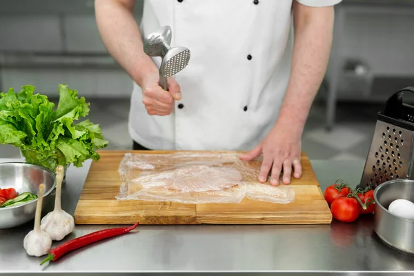Koch schlägt eine Hühnerbrust mit einem Hammer, aus nächster Nähe. Ernährung, gesunde kalorienarme Nahrung, Gewichtsreduktionskonzept. — Stockfoto