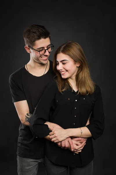 Retrato de jovem casal em roupas pretas vestindo óculos da moda e posando sobre fundo preto — Fotografia de Stock