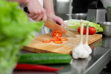 Mutfaktaki şef sebze salatası için taze ve lezzetli sebzeler keser..
