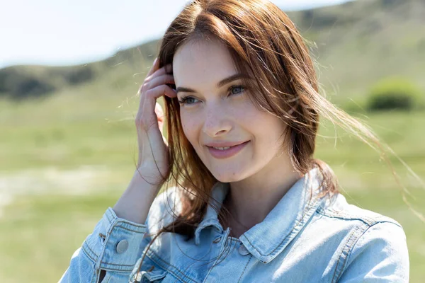 Närbild porträtt av en ung vacker kvinna i naturen på en kulle bakgrund — Stockfoto