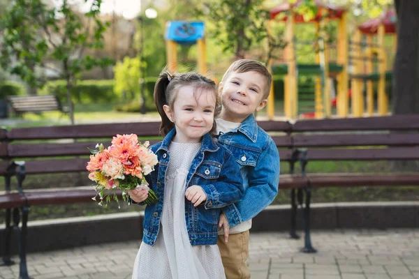 Meisje en jongetje in het park met een boeket bloemen — Stockfoto