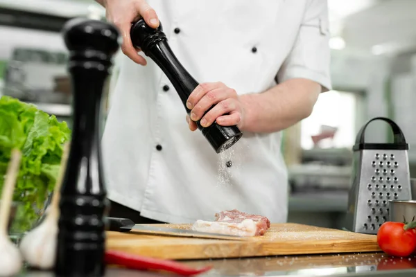Chef gießt mit Salzstreuer Salz auf Rindfleisch. — Stockfoto