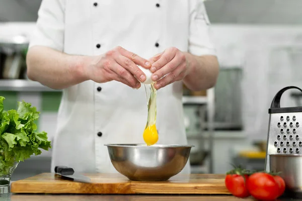 O cozinheiro parte um ovo. Gema de ovo caindo na tigela. — Fotografia de Stock