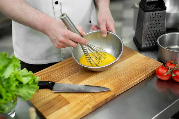 Chef schlägt Eier mit den Händen in eine Schüssel, um ein Omelett mit Gemüse zu machen. — Stockfoto