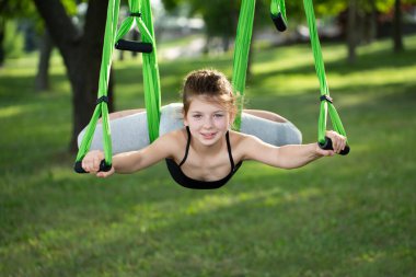Küçük kız parkta hamakla yoga egzersizleri yapıyor..