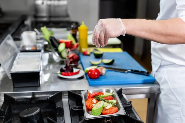 Großaufnahme der Hand eines Kochs, der in einer professionellen Restaurantküche Gemüse einsalzt — Stockfoto