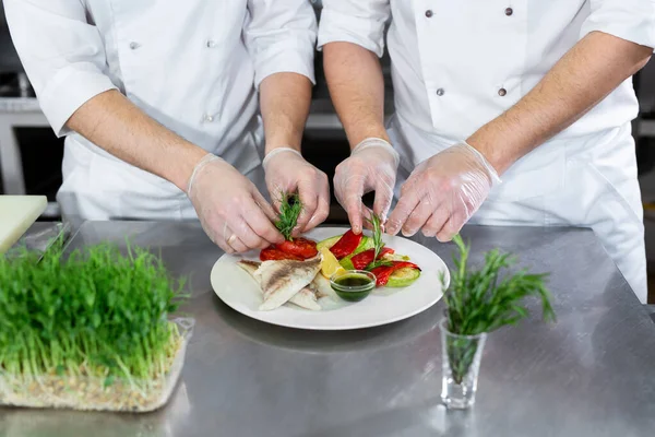 Chef dekoriert Fisch aus Mikrogemüse mit Gemüse in der Küche — Stockfoto