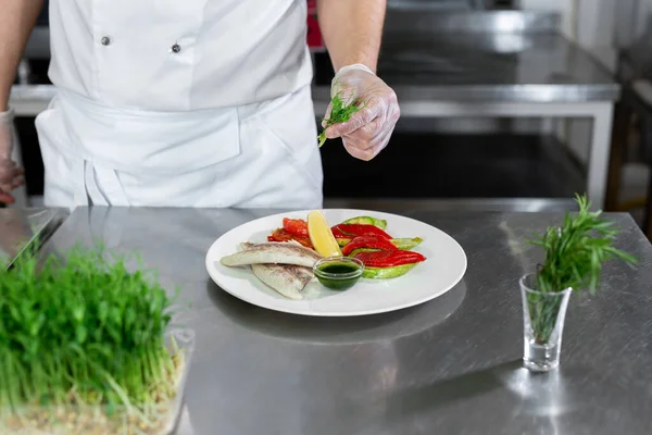 Chef dekoriert Fisch aus Mikrogemüse mit Gemüse in der Küche. — Stockfoto