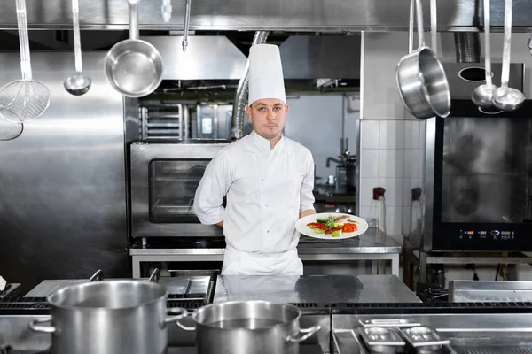 Lo chef di un ristorante tiene un piatto con un piatto pronto. — Foto Stock