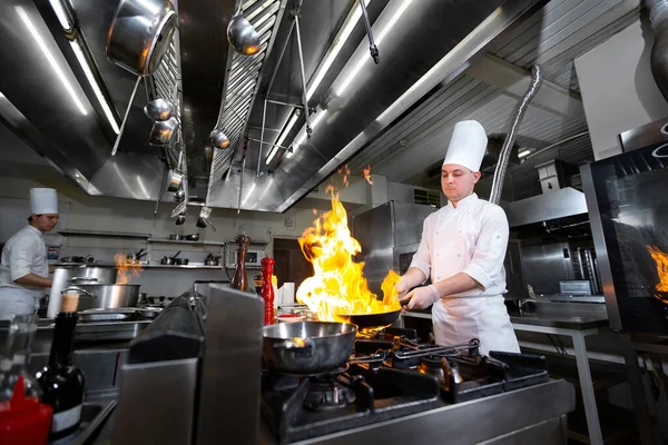 부엌 스토브 위에서 프라이팬에 불을 놓고 요리하는 셰프. — 스톡 사진