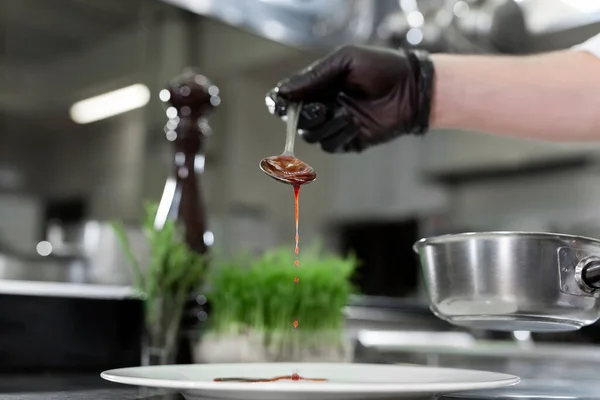 Chef vierte salsa de fresa roja en un plato. — Foto de Stock