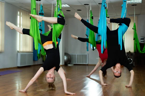 Groep van jonge mooie yogi vrouwen doen luchtyoga praktijk in hangmatten in fitness club — Stockfoto