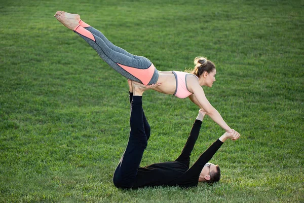 O casal pratica acro ioga no parque na grama. — Fotografia de Stock