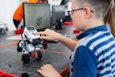 Akıllı okul çocuğu masada oturuyor ve bir okul dersinde robot cihaz yapıyor..