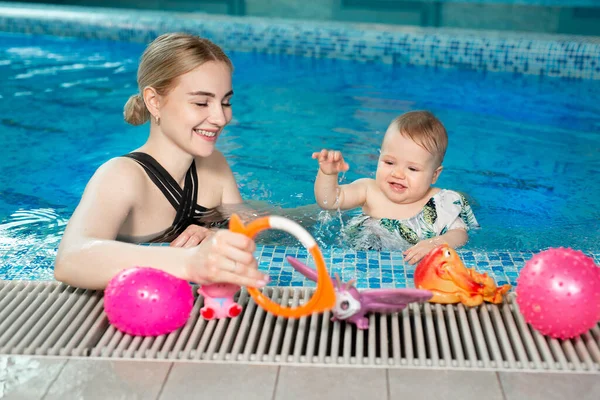 Junge Mutter und ihre kleine Tochter spielen im Pool — Stockfoto