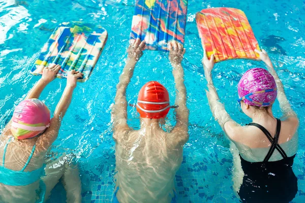Ομάδα αγοριών και κοριτσιών εκπαιδεύονται και μαθαίνουν να κολυμπούν στην πισίνα με έναν εκπαιδευτή. Ανάπτυξη παιδικού αθλητισμού — Φωτογραφία Αρχείου