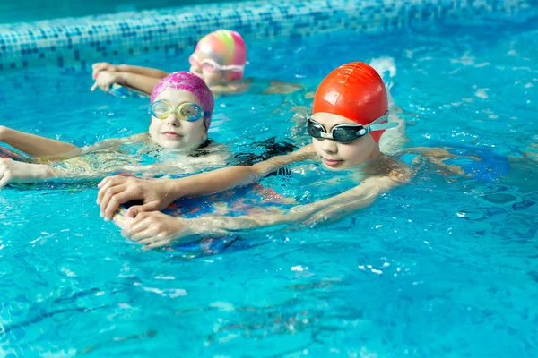 Group of boys and girls train and learn to swim in the pool with an instructor. Development of childrens sports